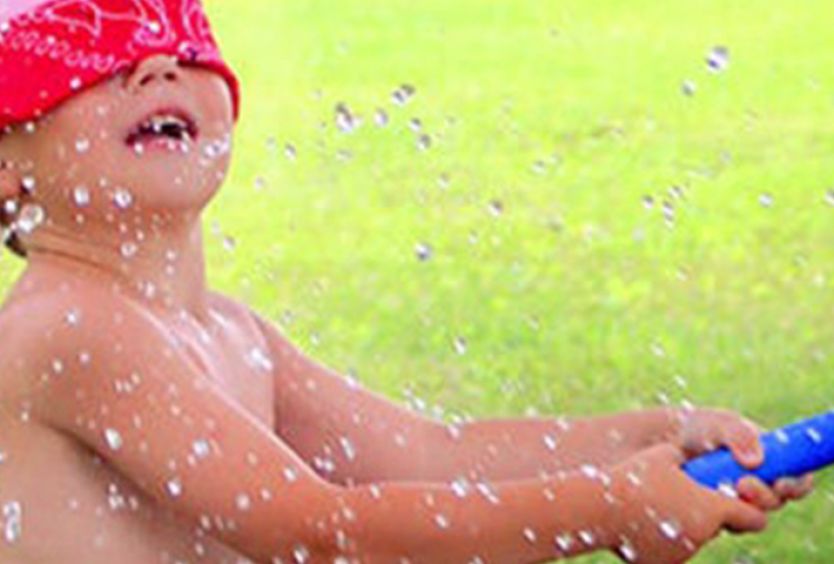 Φωτογραφία απο παιδάκι που πετάει νερό με λάστιχο 