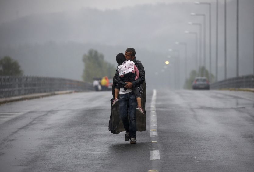 Yannis Behrakis photo of a refugee father carrying his child in the rain